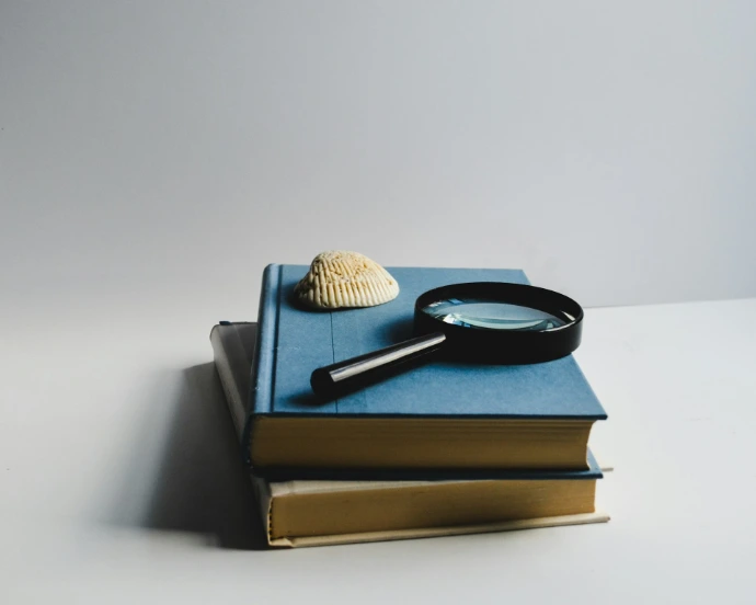 Books, a magnifying glass, and a seashell sit.